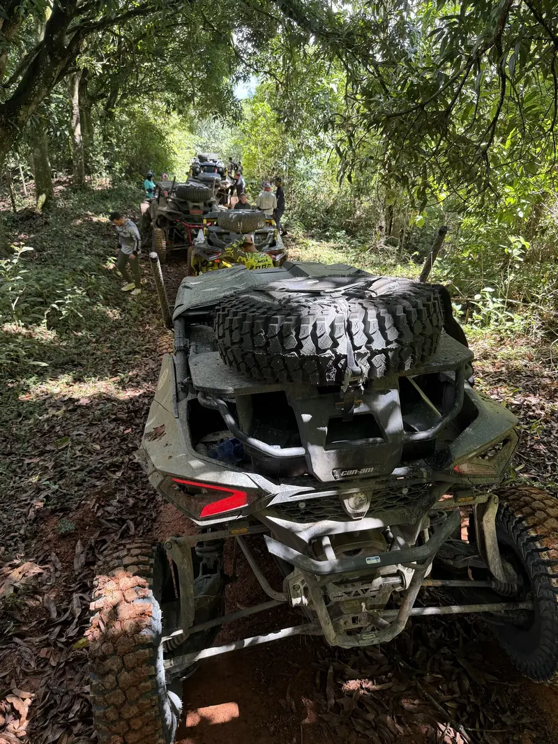 Can-Am con una rueda de repuesto en la parte trasera, en un convoy bajo los árboles