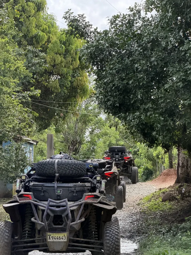 Convoy of Can-Am side-by-sides on a tree-lined village lane in the Dominican Republic