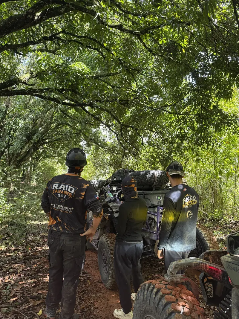 Miembros del equipo de RAID CARAIBES SSV alrededor de un Can-Am detenido en un sendero del bosque